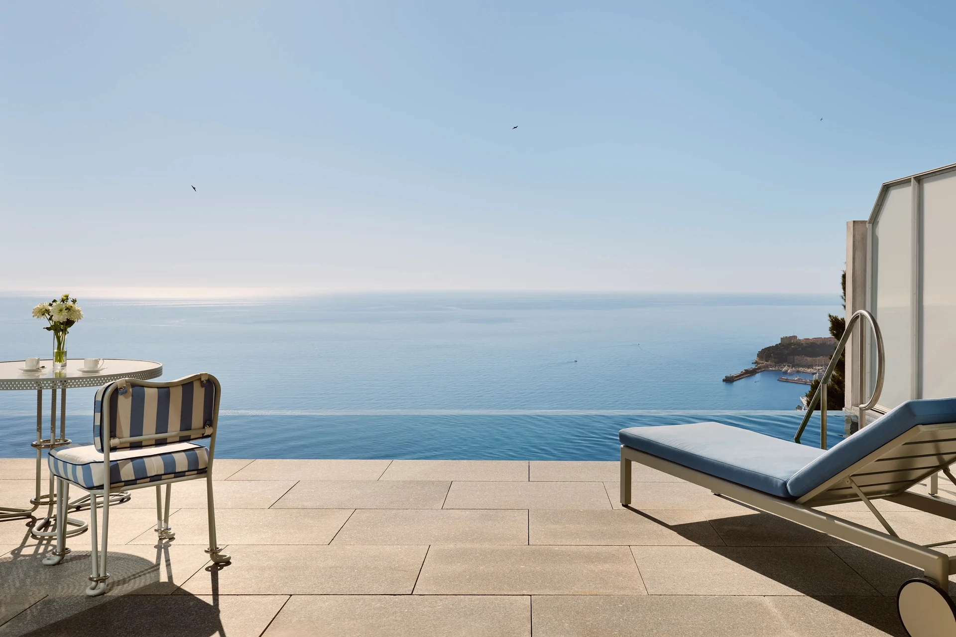 Terrasse privée, coussins bleu azur et bassin à débordement face à la Méditerranée